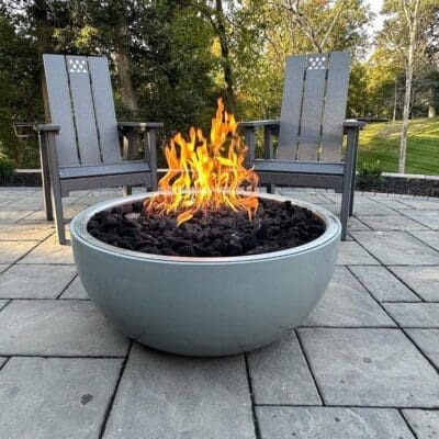 Modern outdoor fire pit with two chairs on a stone patio.